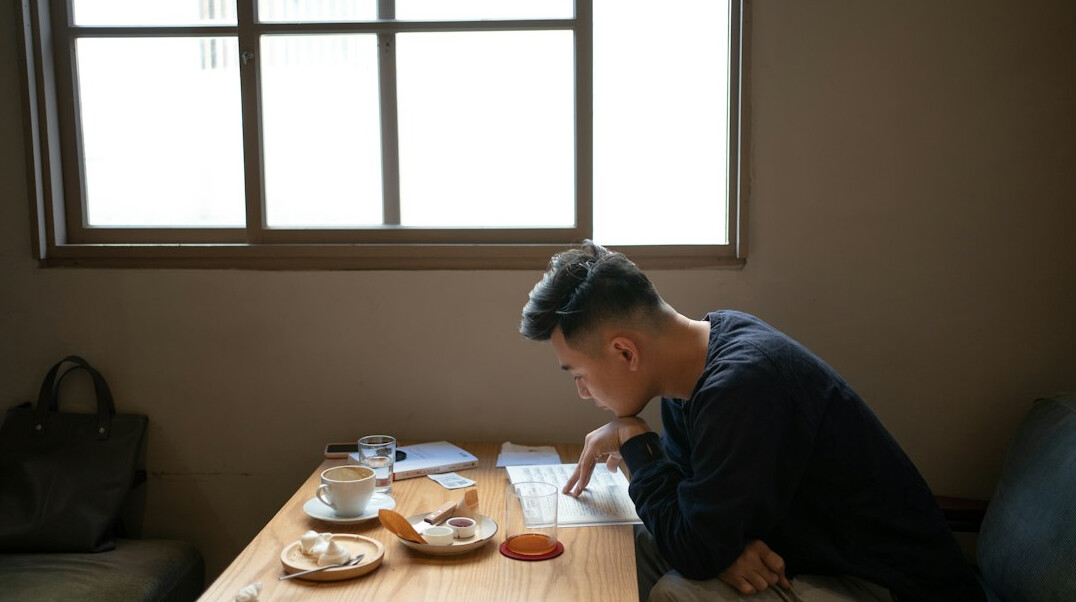 Person writing notes at a cozy Japanese cafe table with tea