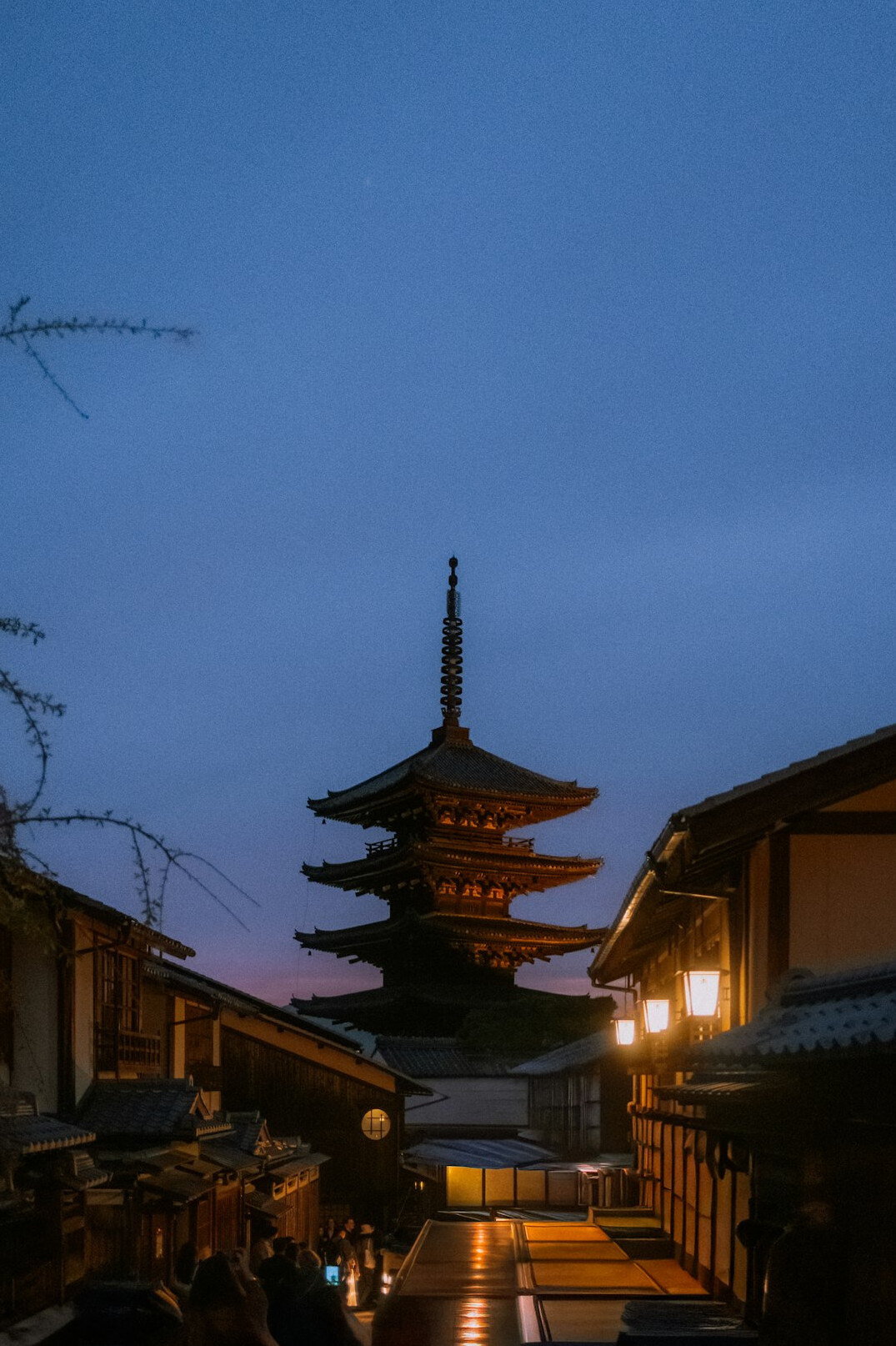 Traditional stone lantern-lined street in Kyoto at dusk with wooden machiya houses